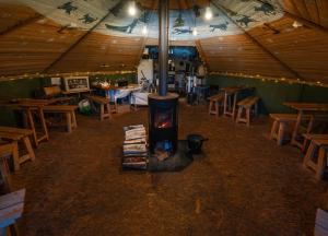 a room with a fireplace in a tent with tables at JVT Cabins in Kiruna