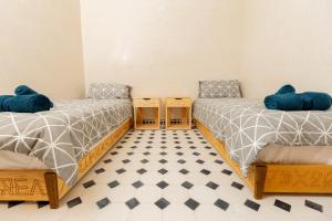 two beds with blue pillows in a room at KASA GUEST Tamraght in Tamraght Ouzdar