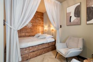a bedroom with a bed with curtains and a chair at Boutique Hotel Alkmaar - City Rooms & Apartments in Alkmaar