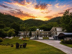 a large building with a sunset in the background at The Comfy By Hotel Mountain Track in Taranna