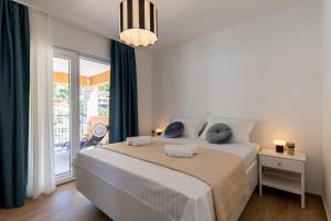 a white bedroom with a large bed with blue pillows at Apartment Jakov Grscica in Prizba