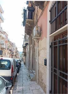 a narrow street with cars parked on the side at Casetta giuly in Ragusa