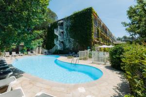 a swimming pool in front of a building at Villa Borghese, The Originals Relais in Gréoux-les-Bains