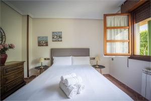 a bedroom with a large white bed with towels on it at Casa Rural El FerJo in Colunga