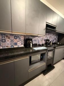 a kitchen with white cabinets and a stove top oven at Apartamento Parque Trianon Exclusive in Araçatuba