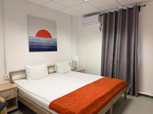 a bedroom with a bed with white sheets and an orange blanket at Birlik in Tengiz +72 photos