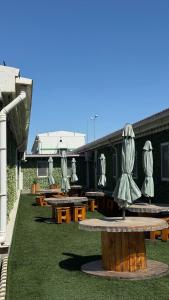 a patio with tables and umbrellas on the grass at Birlik in Tengiz