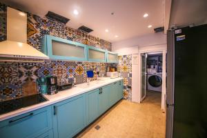 a kitchen with blue cabinets and tiles on the wall at Vega 43 Hostel in Sarandë