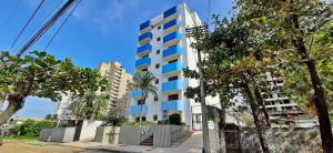 a tall white building with blue windows at Canto do Atlântico Hotel in Guarujá