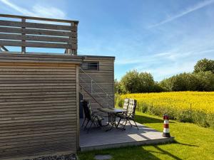 a wooden deck with a table and chairs next to a field at Tiny Haus Schwalbe in Groß Kordshagen