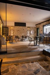 a room with chairs and tables and a stone wall at Wind Alasata in Çeşme