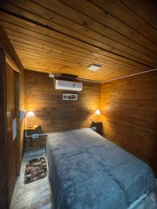 a bedroom with a large bed in a wooden wall at Cabañas las fulanas in Villa Giardino