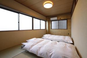 a room with two beds in it with windows at Konrai Hotel Matsumoto in Matsumoto