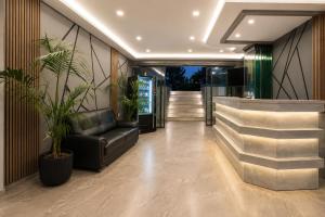 a lobby with a black leather couch and plants at Perla Halkidiki in Kallithea Halkidikis