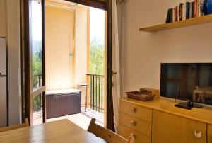 a living room with a television on a dresser and a balcony at Barzio Coldogna 5 in Barzio