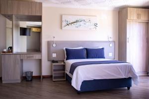 a bedroom with a large bed with blue pillows at Regal Inn Ballito in Ballito