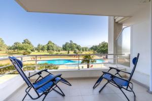 two chairs on a balcony with a view of a pool at Green Flat - Appt proche des Sables dOlonnes in LʼAiguillon-sur-Vie