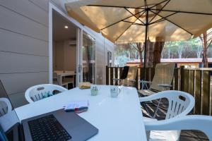 a laptop on a white table with chairs and an umbrella at Camping Iscrixedda in Lotzorai +6 photos
