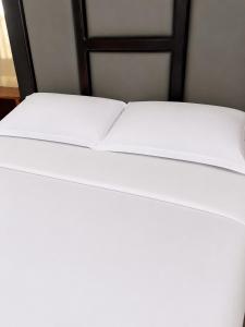 a bed with white sheets and a black frame at Home23 Apartments in Jinja