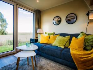 a living room with a blue couch with yellow pillows at Tiny Haus Schwalbe in Groß Kordshagen +32 photos