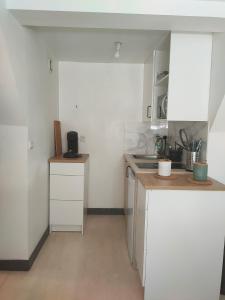 a small kitchen with white cabinets and a sink at Le petit Treguier in Tréguier