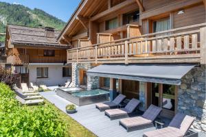 a house with a deck with chairs and a swimming pool at Hôtel Chalet & Spa Le Delta in Le Grand-Bornand