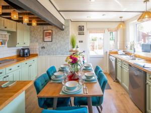 a kitchen with a wooden table and blue chairs at 4 Bed in Dothan Ty Croes oc-m44701 in Llanfaelog