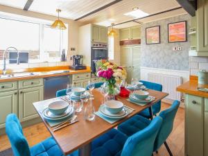 a kitchen with a wooden table and blue chairs at 4 Bed in Dothan Ty Croes oc-m44701 in Llanfaelog +11 photos