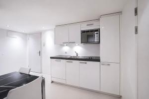 a kitchen with white cabinets and a sink and a table at VISIONAPARTMENTS Binzmühlestrasse 50 - self check-in in Zurich