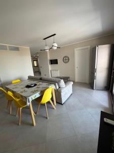 ein Wohnzimmer mit einem Tisch und gelben Stühlen in der Unterkunft Villa ManuCamp in Reggio di Calabria