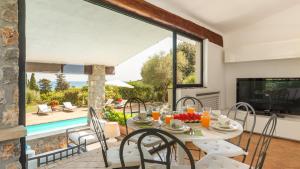 a dining room with a table and chairs and a pool at VILLA ALTHAEA 6, Emma Villas in Orbetello