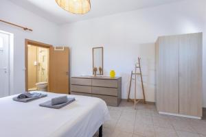 a white bedroom with a bed and a dresser at Local Guesthouse in Sagres