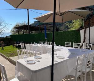 a long table with white chairs and umbrellas at Villa Morena in Trnovo