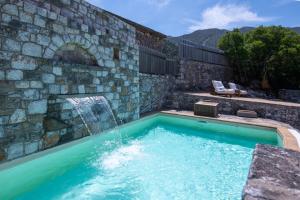 a swimming pool with a waterfall and a stone wall at Traditional Villas Askyfou in Karés