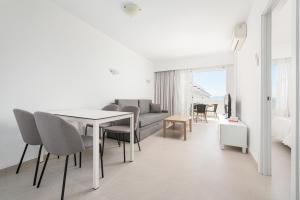 a white living room with a table and a couch at Apartamentos Siesta I in Port d'Alcudia