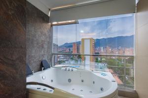 a bath tub in a bathroom with a large window at Hotel Piso 12 in Bello