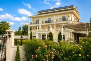 a large white house with a fence and flowers at Aleksov Complex Aleksion Palace in Ognyanovo