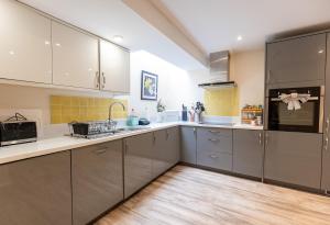 a kitchen with gray cabinets and yellow tiles at COTTON HOUSE - Peak District Escape, Walks, Canal & Cromford Mill in Matlock +25 photos