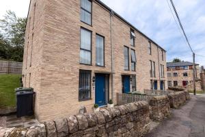 a brick building with blue doors and a stone wall at COTTON HOUSE - Peak District Escape, Walks, Canal & Cromford Mill in Matlock
