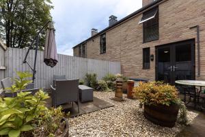 a patio with a table and an umbrella and some plants at COTTON HOUSE - Peak District Escape, Walks, Canal & Cromford Mill in Matlock
