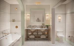 a bathroom with a sink and a tub and a toilet at The Nora Hotel in West Palm Beach