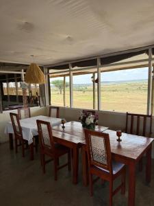 a dining room with a table and chairs and windows at Narasha homestay in Talek