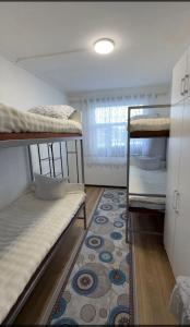 a dorm room with three bunk beds and a rug at Janai Guest house in Karakol