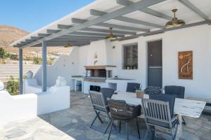 a patio with chairs and a table and a fireplace at Villa Fotis in Ano Syros