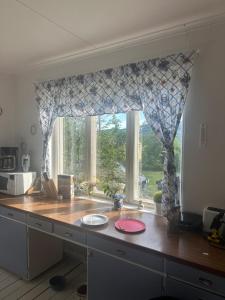 a kitchen counter with a window with a window curtain at Nordic Villa Undrom in Undrom +12 photos