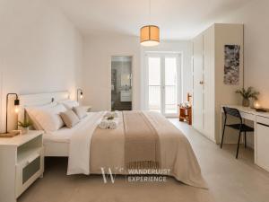 a white bedroom with a large bed and a desk at Wanderlust Experience Pumetta Apartment in Bitonto