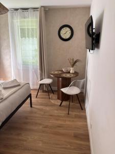 a bedroom with a table and a clock on the wall at Appartement proche Université Arras, parking gratuit et privé in Arras