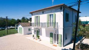 a white house with green doors and a balcony at Dimora Coloré in Nereto