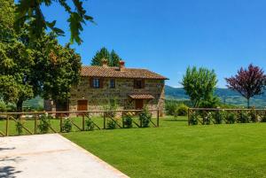 a stone house in a field with a fence at Casale Donatelli in Radicofani