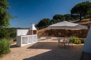 a table and an umbrella and a table and chairs at Quinta da Barradinha in Odemira